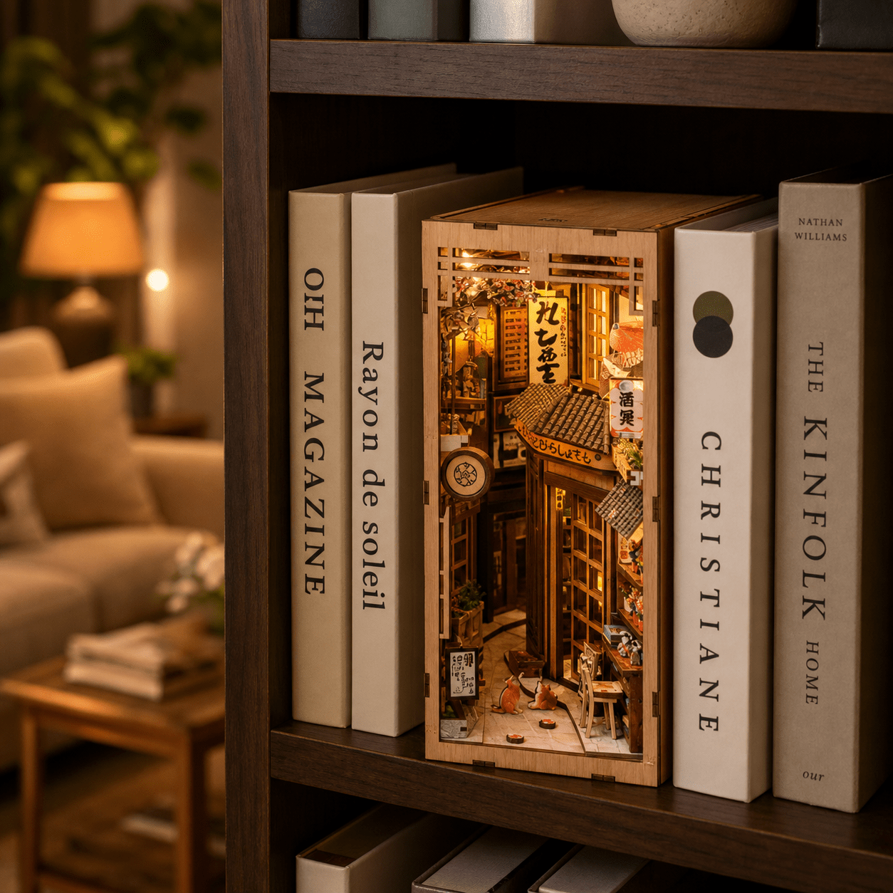 Japanisches Cat Alley Book Nook im Bücherregal zwischen Büchern, warme LED-Beleuchtung zeigt eine detailreiche Miniaturgasse mit Katzen und Holzdesign.