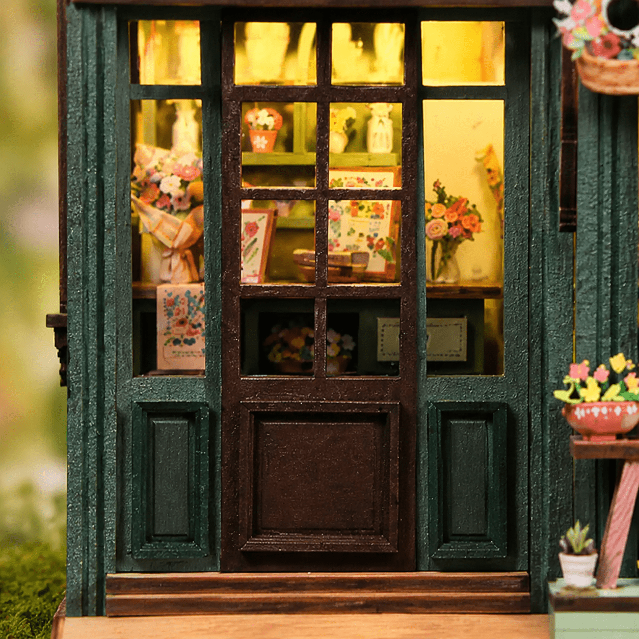 Flower House Book Nook Miniatur mit grüner Tür, großen Fenstern, Blumen und warm beleuchtetem Innenraum