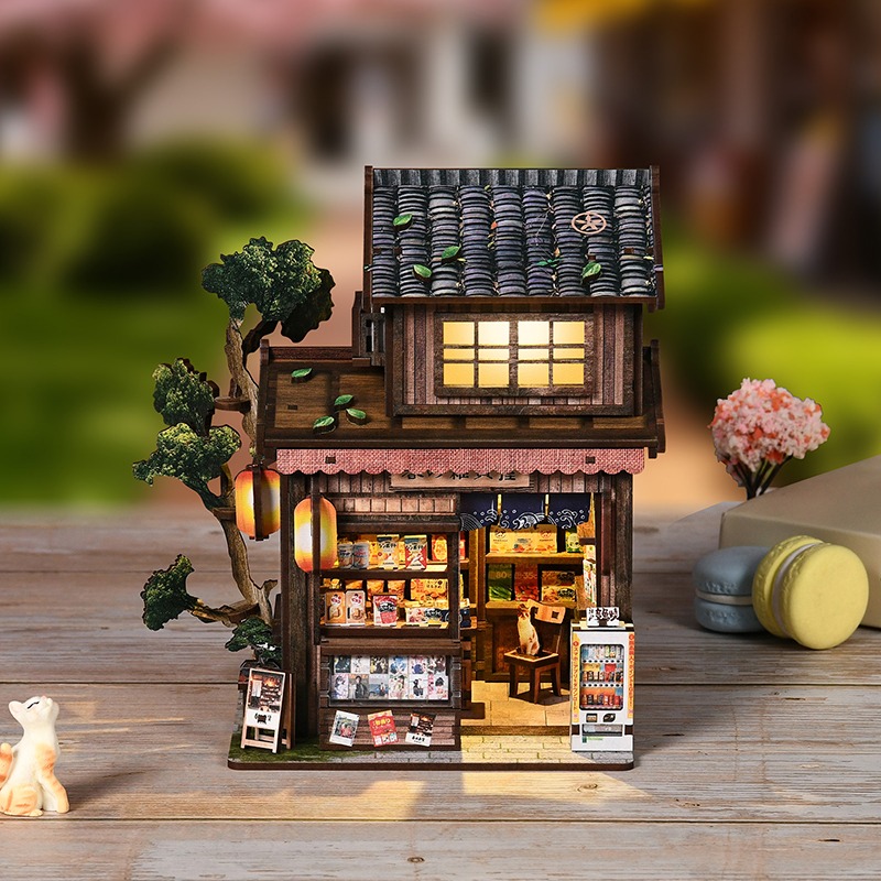 „Kasuga Grocery Store“-Book-Nook – eine japanische Miniatur-Ladenkulisse mit warmer LED-Beleuchtung, traditioneller Holzfassade, Verkaufsregalen, Verkaufsautomat, Baumdekoration und gemütlicher Straßenatmosphäre.