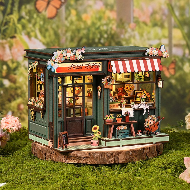 Aura Verde Flower Room Book Nook – eine Miniatur-Blumenhandlung mit warmer LED-Beleuchtung, grüner Fassadengestaltung, farbenfrohen Blumen, Schmetterlingsdekorationen und einer detailreichen DIY-Miniaturszene aus Holz.