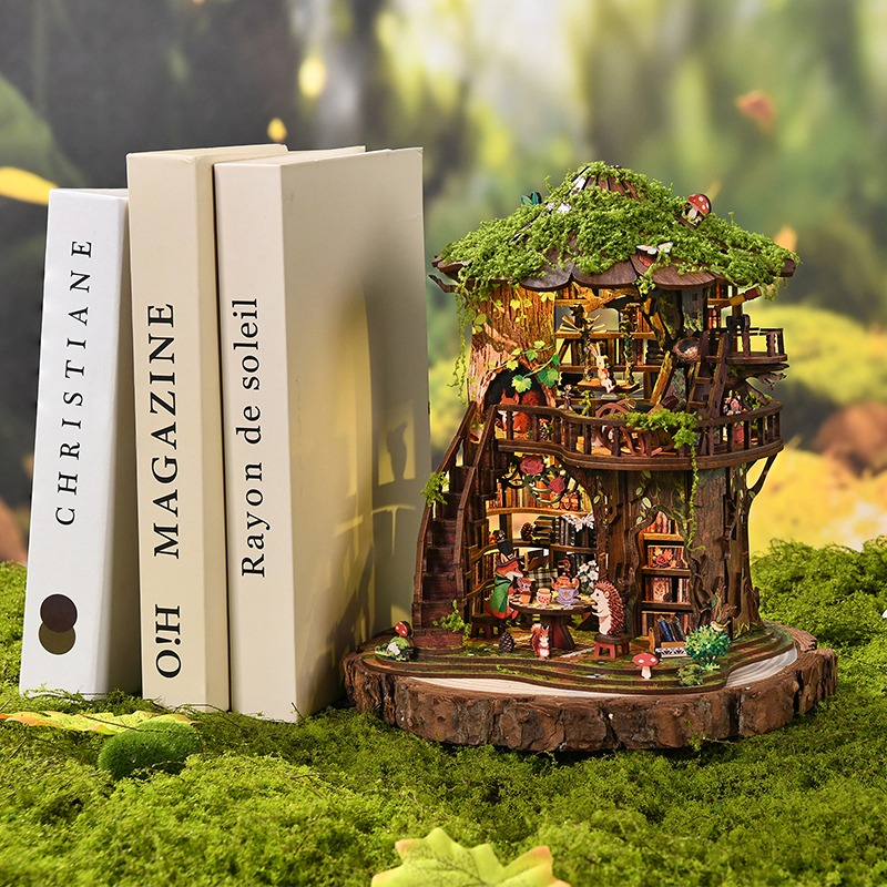 Forest Tea House-Buchstütze (Book Nook) mit magischem Baumhaus-Design: Moosdach, Walddekorationen, Miniaturtieren, gemütlichem Teetisch und warmer Waldatmosphäre.