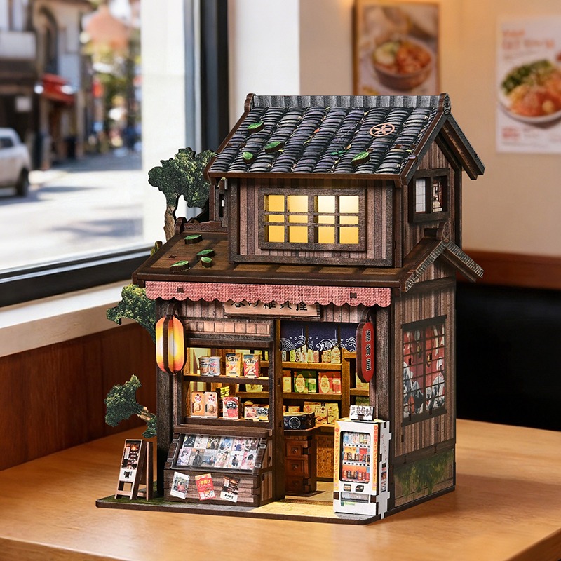 Book Nook im Stil eines japanischen Gemischtwarenladens – mit traditionellem Holzdesign, Miniaturregalen, Verkaufsautomat, Laternenbeleuchtung und detailreicher Gestaltung einer japanischen Straßenszene.