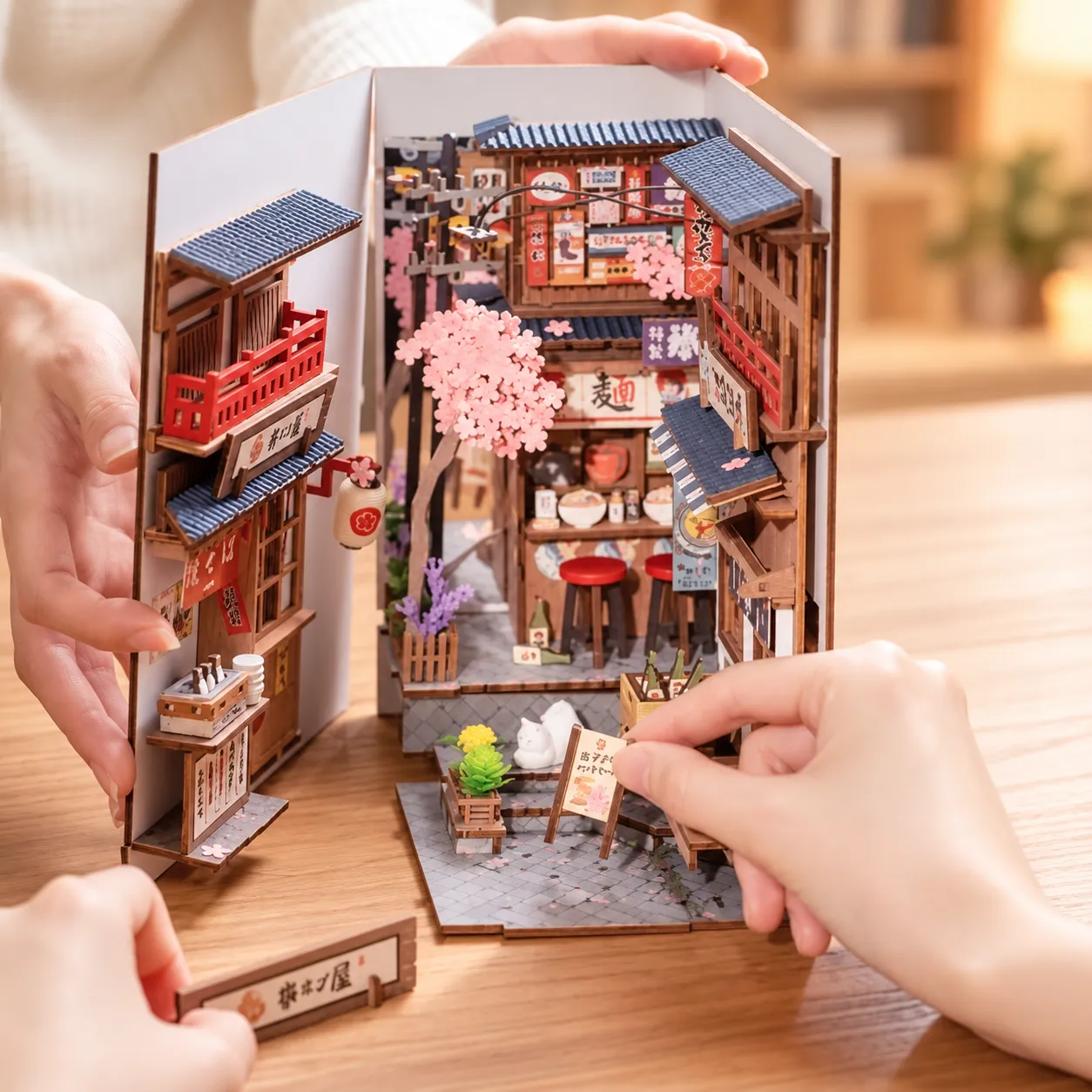 Sakura Book Nook beim Zusammenbau mit Händen auf einem Holztisch